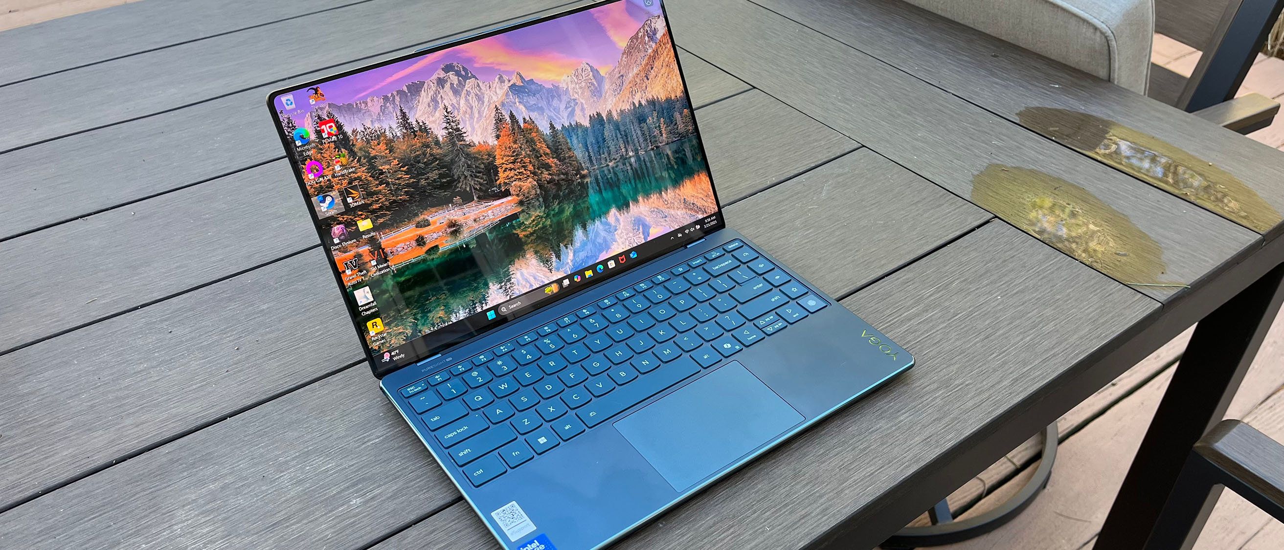 A Lenovo Yoga Slim 9i sitting on a picnic table outside