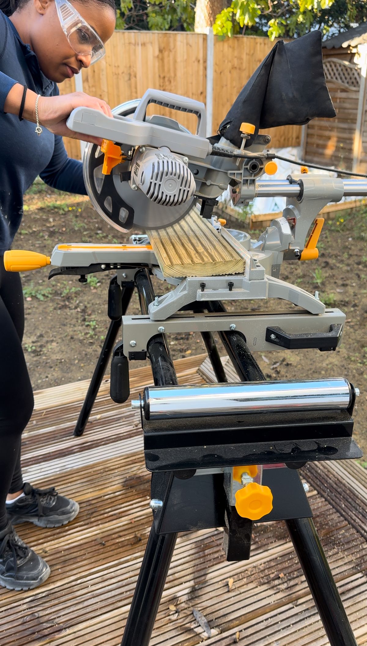 A woman uses a circular saw to cut a plank of wood