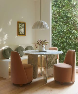 banquette breakfast corner nook with a marble round table and pink velvet chairs