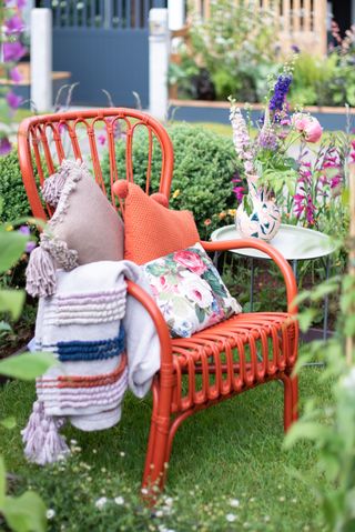 boho garden chair painted in burnt orange with colourful cushions and throws