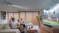 A family watching a football game beamed from a projector overhead