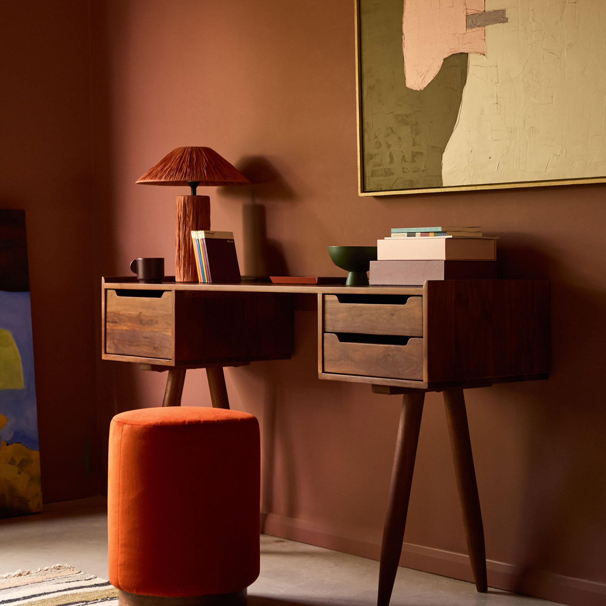 Red room with mahogany desk, orange stool and large canvas