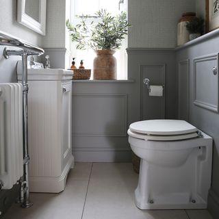 Grey panelled bathroom with white wooden sink and toilet