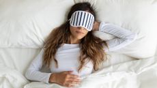 Calm peaceful young lady wearing sleeping mask, dreaming