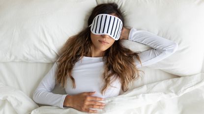 Calm peaceful young lady wearing sleeping mask, dreaming