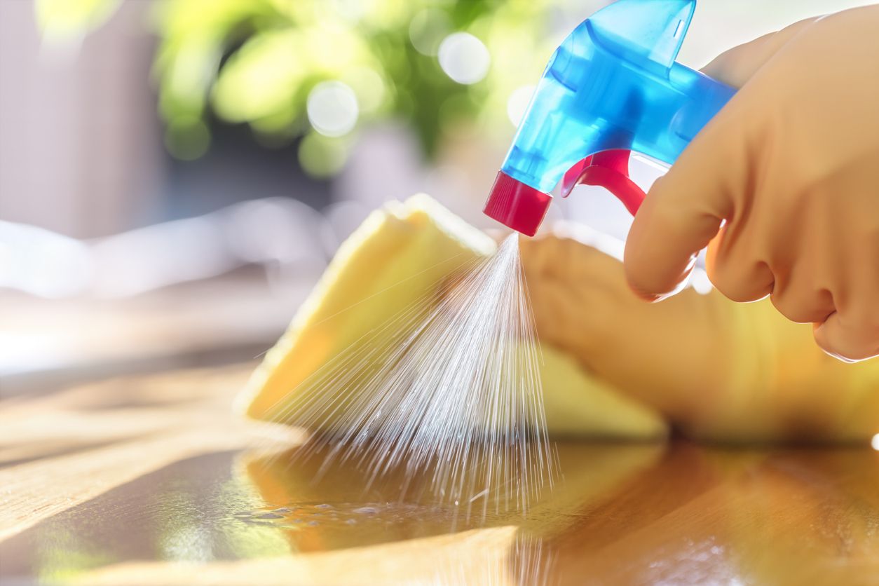 A person sprays a counter with cleaning solution.