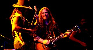 Dickey Betts and Warren Haynes live onstage with the Allman Brothers Band in 1992. Haynes wears a patterned shit and plays his Les Paul Standard.