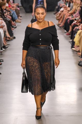 Paloma Elsesser wearing an off-the-shoulder cardigan with a sheer lace skirt at the Michael Kors Collection show.