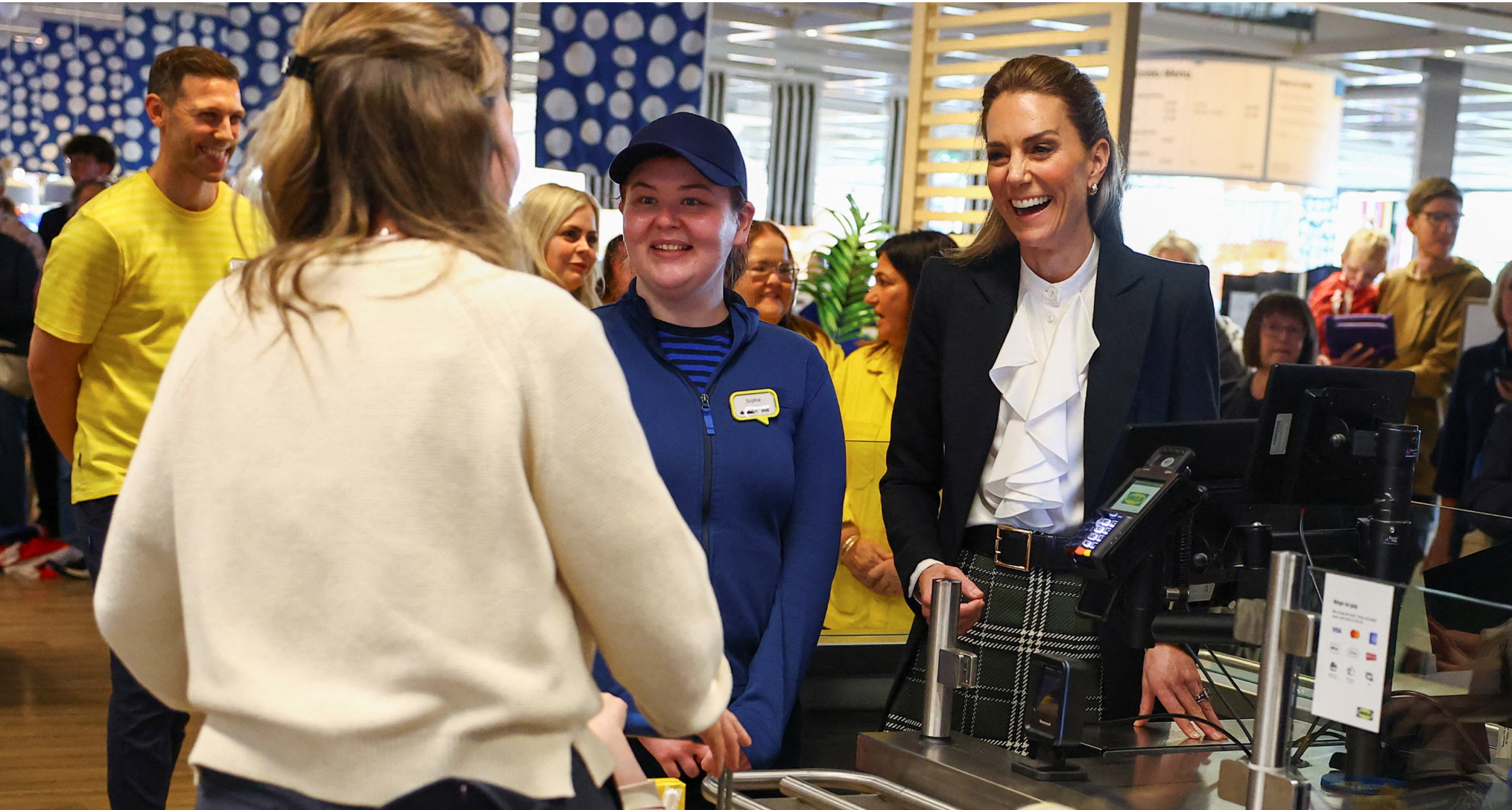 Princess Kate standing behind a cash register at IKEA serving a customer