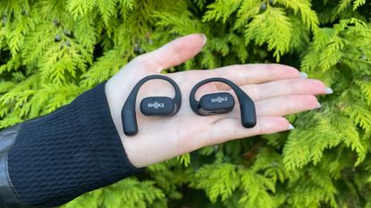 Female cyclist holding the Shokz OpenFit headphones