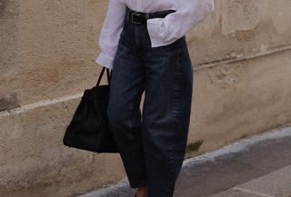 Woman wearing a button-down and barrel-leg jeans.