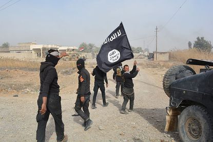 Iraqi government forces carry an ISIS flag they say they captured