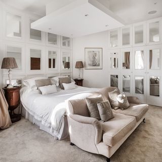 bedroom with white mirrored wall and sofa