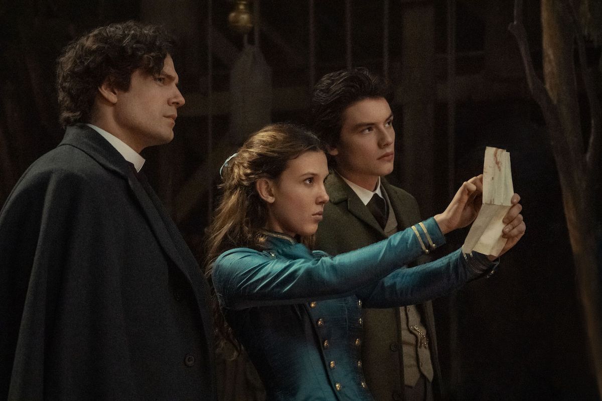 Millie Bobby Brown, Henry Cavill and Louis Partridge looking at piece of paper in Enola Holmes 2
