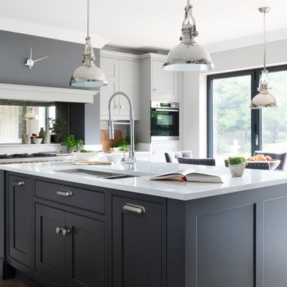 A modern kitchen with bifold doors, navy kitchen island and statement pendant light fixtures overhead