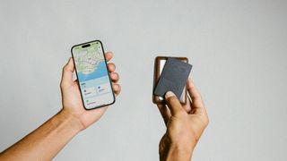 Nomad Tracking Card in hand next to an iPhone with Find My