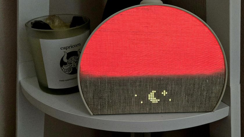 A Hatch Restore 3 Sunrise Alarm Clock glowing red on a shelf next to a gemstone candle