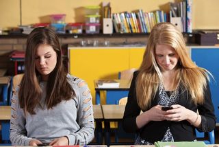 Teen girls texting in school.