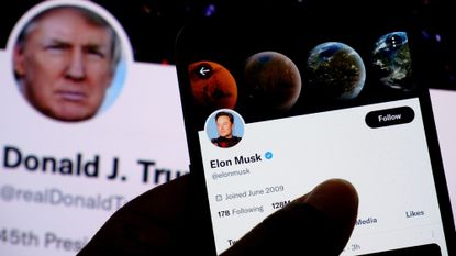 In this photo illustration, Elon Musk&#039;s twitter account is seen displayed on a smartphone with Donald Trump&#039;s Twitter account in background