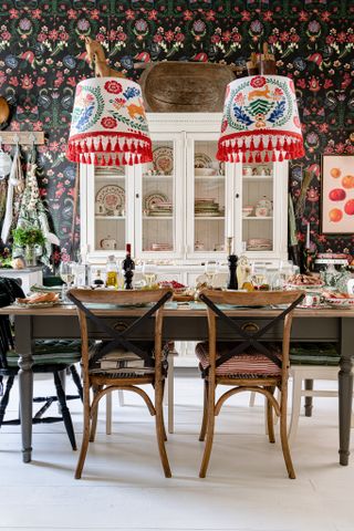 eclectic dining room with modern floral wallpaper and bold print pendant lights, wooden table and chair, white floor, white dresser