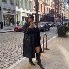 model wears black mini dress with trench coat and tall boots