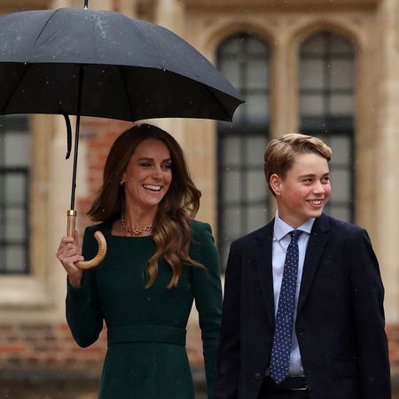 Princess Kate smiling and holding an umbrella with Prince George