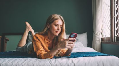 woman using phone on bed