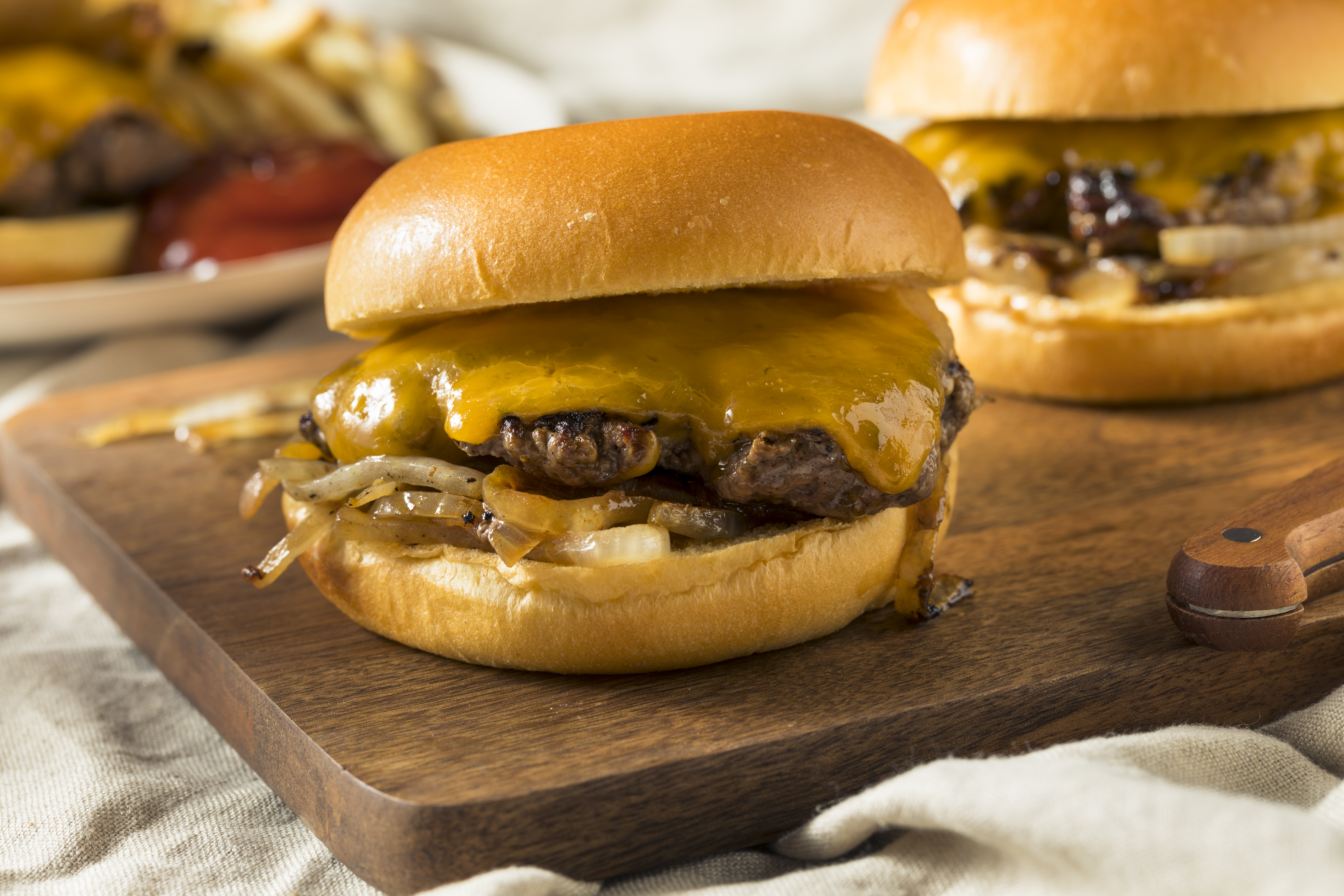 Two onion burgers on a wooden board