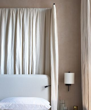 Neutral bedroom with cream canopy. White bedding, beige painted walls