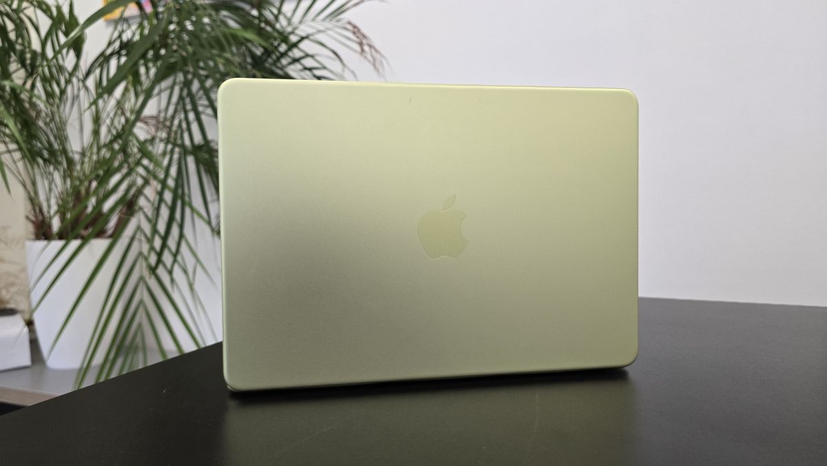 MacBook Neo laptop on a desk with plant in background