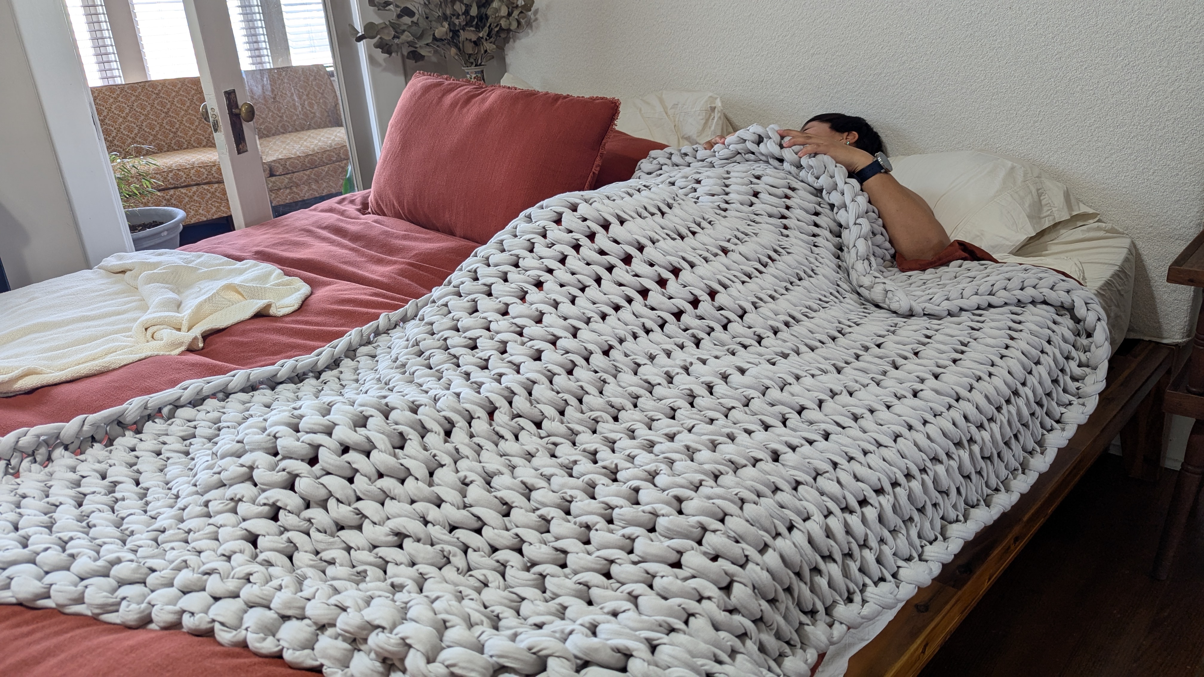 Woman sleeping on the bed with a grey weighted blanket draped over her