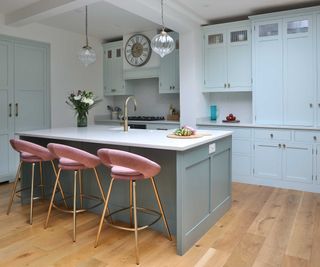 pale blue kitchen with large kitchen island with pink bar stools