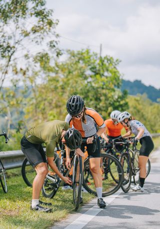 Cyclist helps another with her front wheel