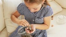 Young girl in a gingham dress counting coins from a jar