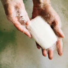 Sudsy hands holding a white bar of soap