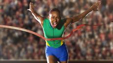 A runner looks intense as she breaks through the tape at the finish line of a race. 