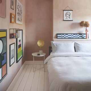 Light pink-painted bedroom with a gallery wall and painted floor boards in white