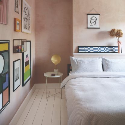 Light pink-painted bedroom with a gallery wall and painted floor boards in white