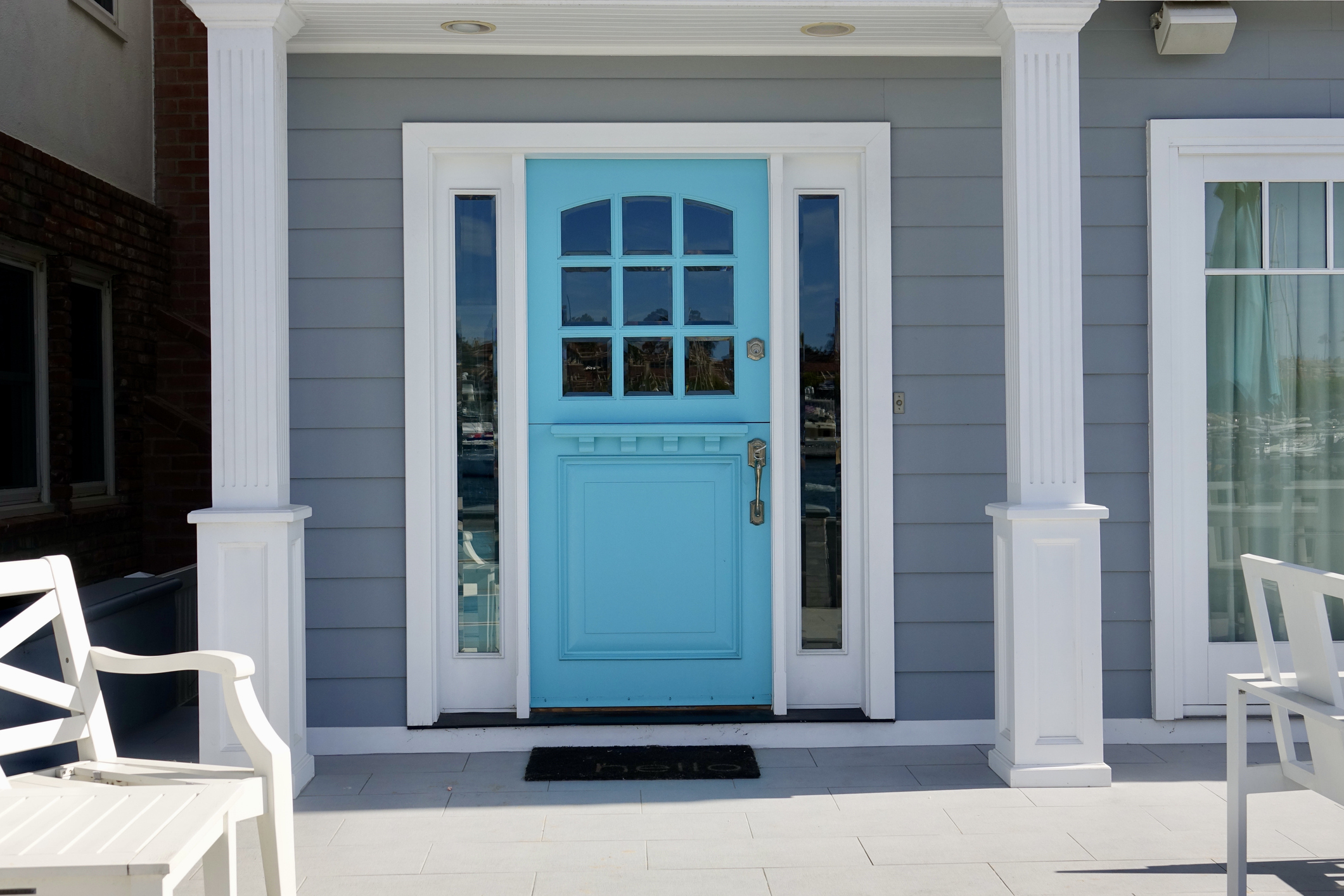Front porch of gray cottage with aqua blue Dutch door.
