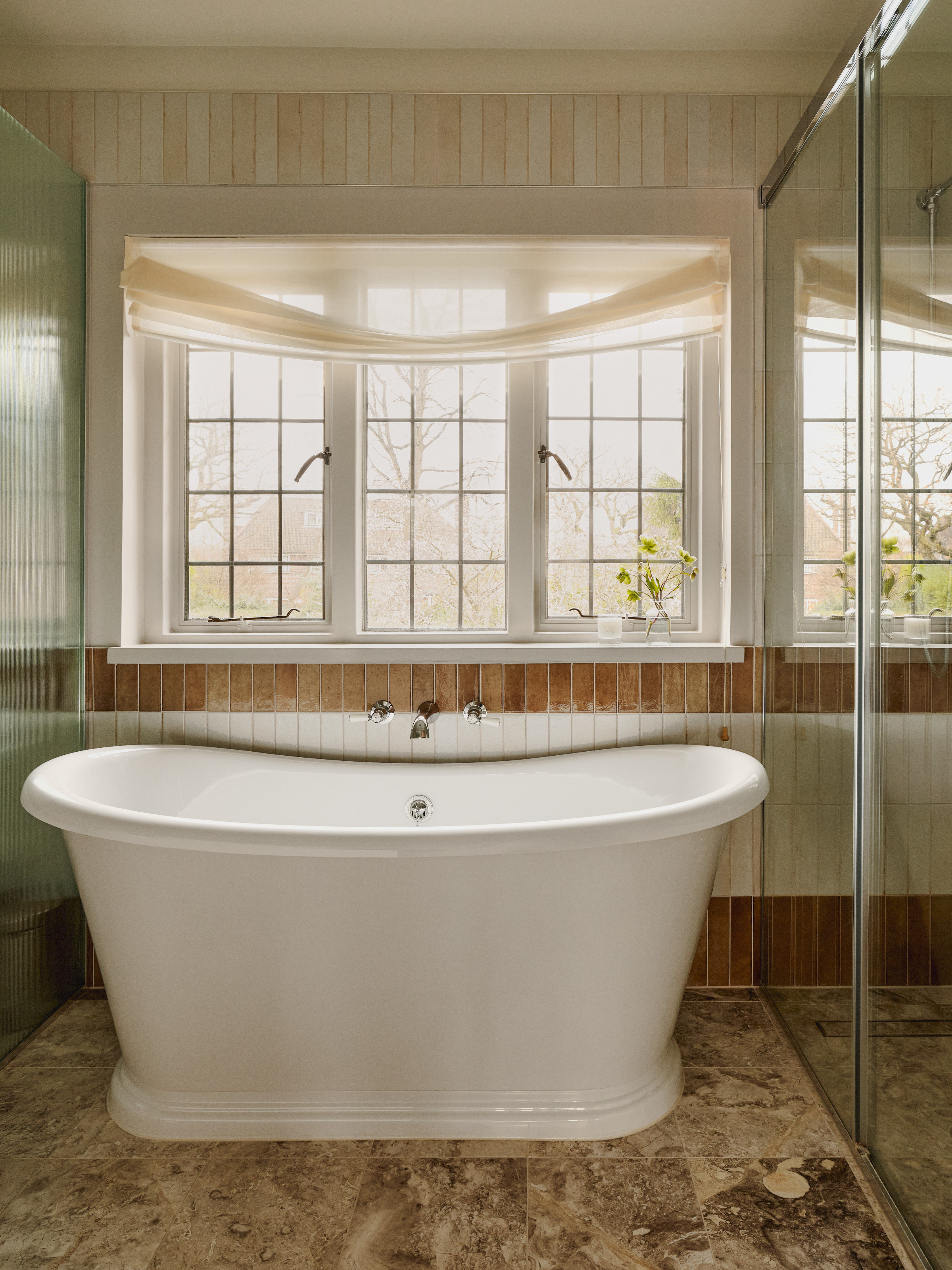 Bathroom with terracotta and white tiles and a white freestanding bathtub