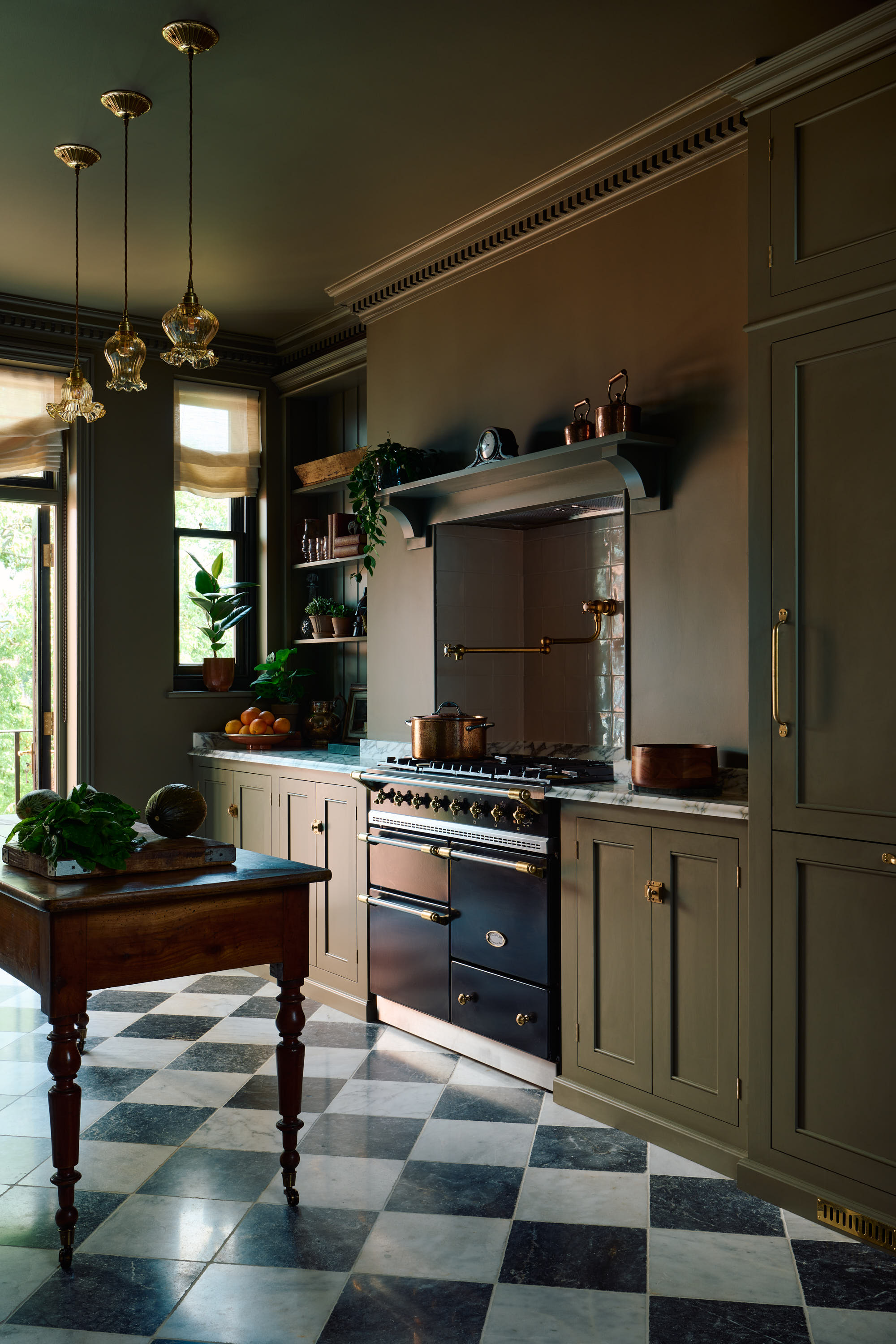 traditional kitchen with checkerboard flooring and a range cooker, color drenched in an olive green shade