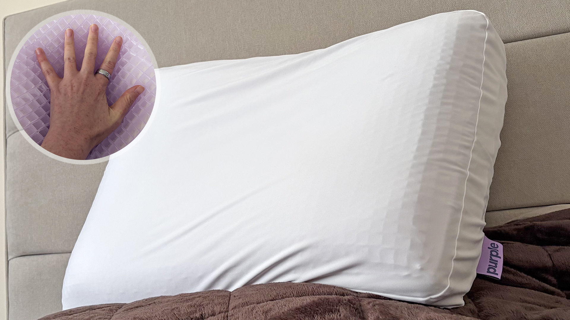 The Purple DreamLayer Pillow on the bed in our reviewer's bedroom. In the Top left corner is a close up of a hand on the Purple GelFlex Grid.