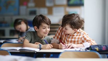 Two young boys work on a project in a classroom.