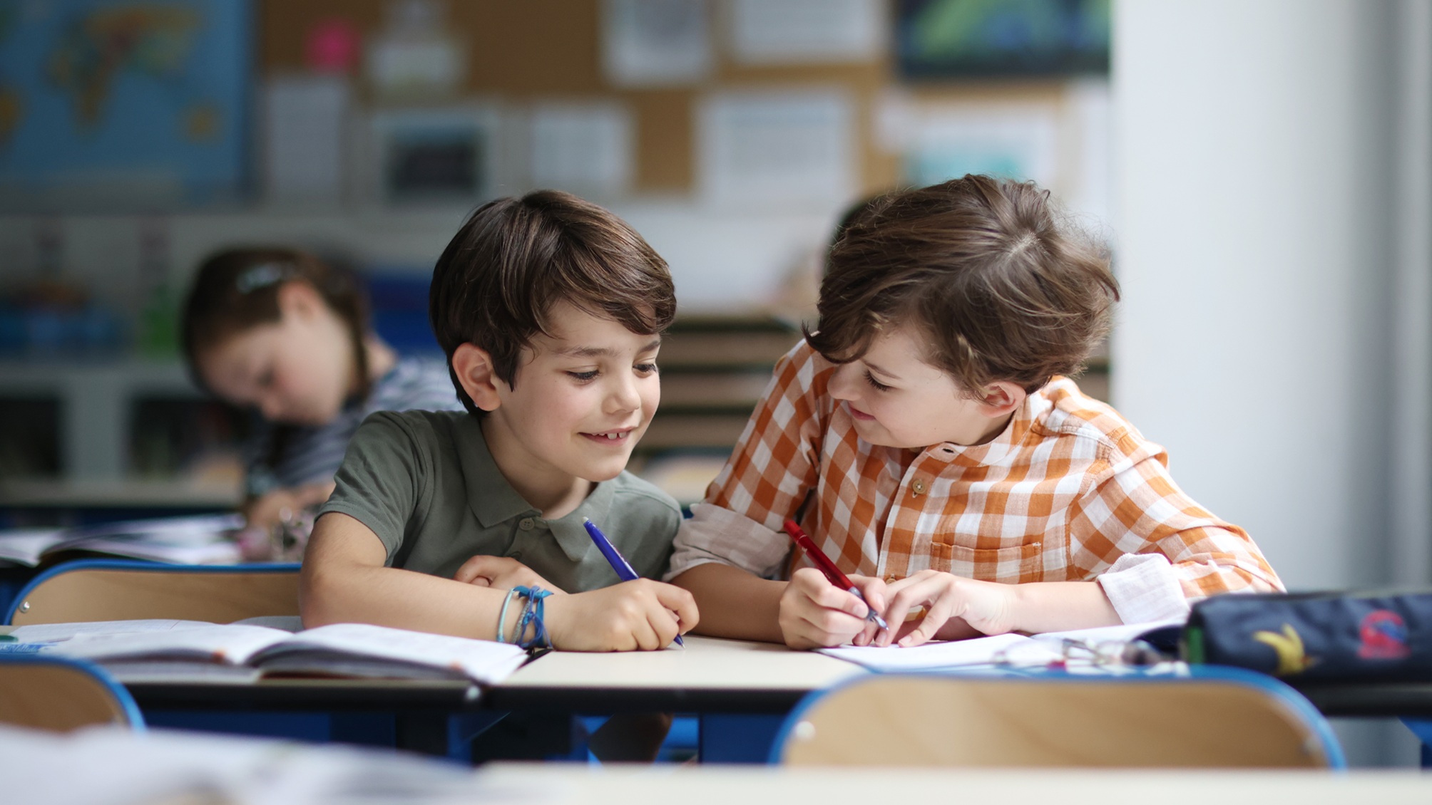 Two young boys work on a project in a classroom.