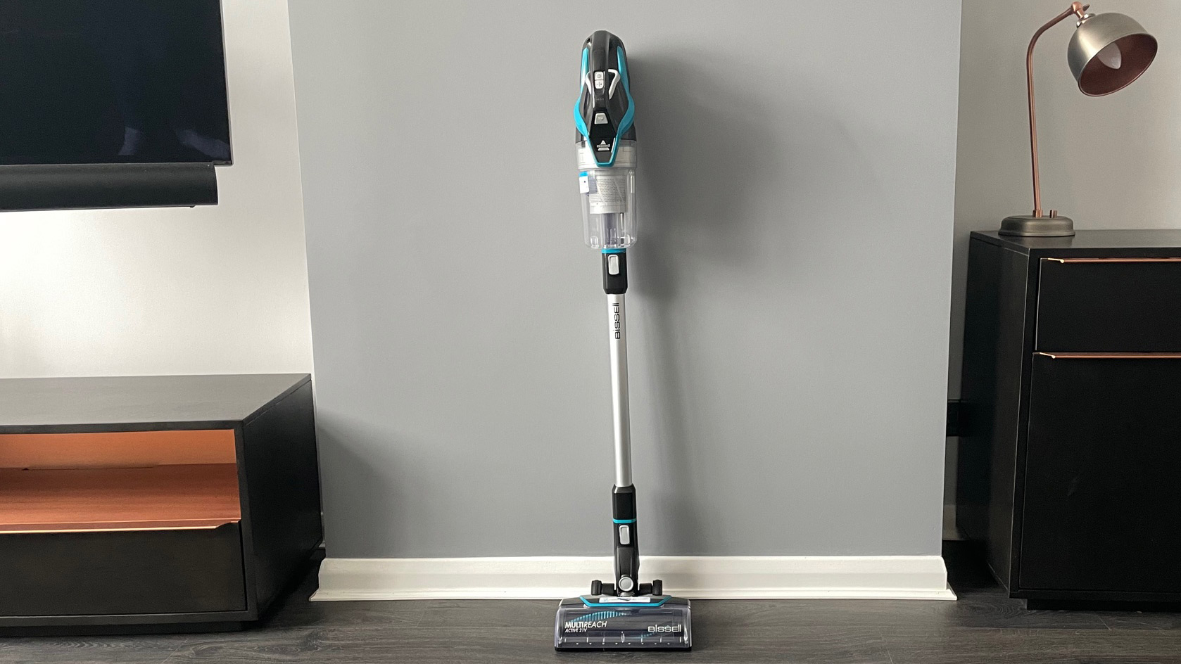 The Bissell CleanView Pet Slim Cordless Stick Vacuum leaning up against a grey wall