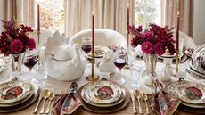 a thanksgiving table decorated with ornate plates, glasses, ceramic turkeys and pink flowers