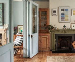 two connecting living room spaces - one painted pale blue with blue doors and one neutral with a blue ceiling and wooden floor