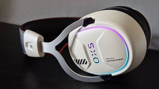 Photo taken by writer Rosalie Newcombe of the OXS Storm G2 wireless gaming headset sitting on its side on a black shelf with its RGB lighting on.