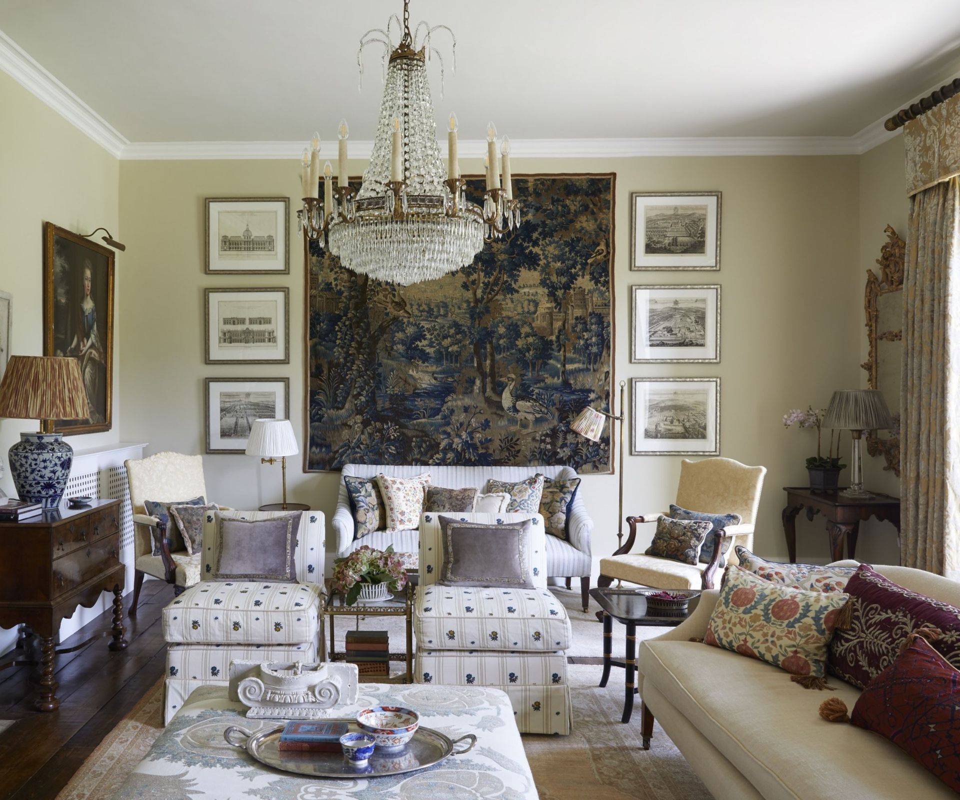 Traditional living room with tapestry on the wall, antique paintings and upholstered armchairs