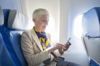 Business woman using smart phone at plane